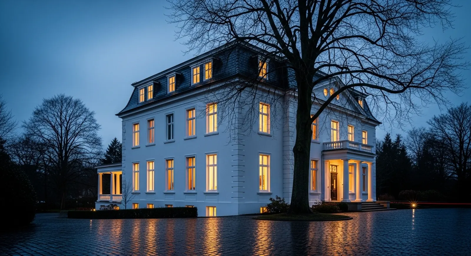 Stadtvilla bei Abenddämmerung mit warm beleuchteten Fenstern